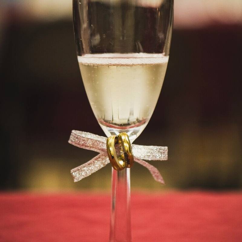 A champagne flute for the toast with two gold rings tied to the stem in glitter ribbon