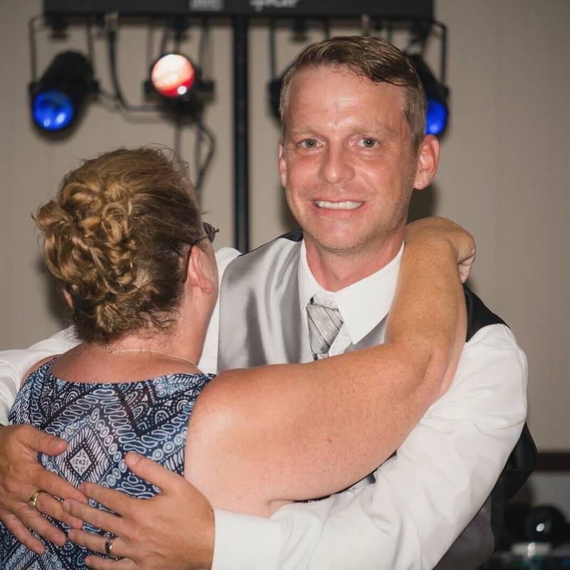 Jay hugs his mom on the dance floor under the DJ lights at the Owego VFW reception