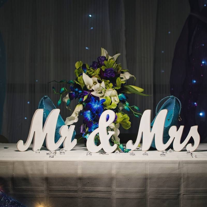 A white Mr and Mrs sign in front of a bouquet and a pair of teal glitter heels on the head table at the Owego VFW